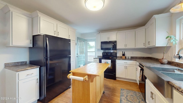 1010 Orange St, Newport, NC 28570 - kitchen featuring black appliances, white cabinets, a sink, and light wood finished floors