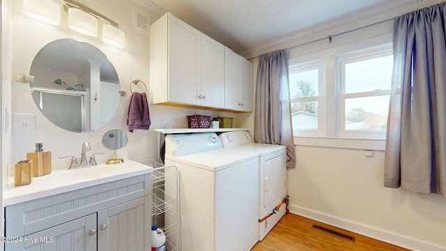 washroom featuring sink, cabinets, separate washer and dryer, crown molding, and light hardwood / wood-style floors