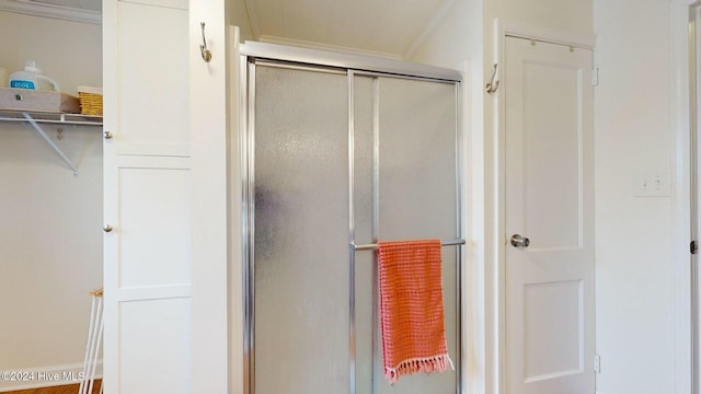 bathroom featuring a shower with shower door and crown molding