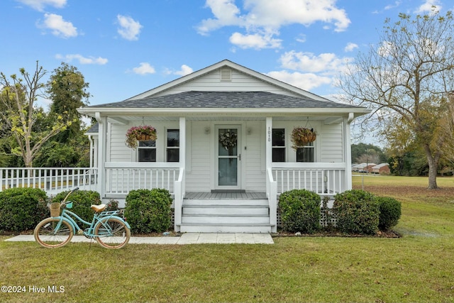 bungalow featuring covered porch and a front yard