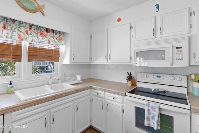 kitchen featuring white appliances, sink, ornamental molding, and white cabinets