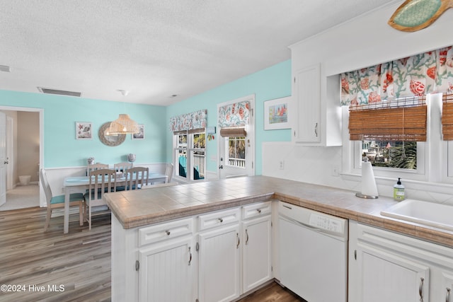 kitchen with kitchen peninsula, white cabinetry, a healthy amount of sunlight, and dishwasher