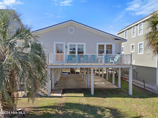 back of property with a lawn, a carport, and a wooden deck