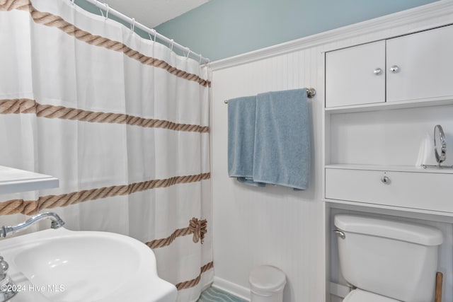 bathroom featuring a shower with shower curtain, sink, and toilet