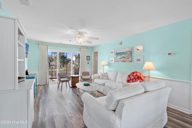 living room featuring hardwood / wood-style floors, ceiling fan, and a textured ceiling