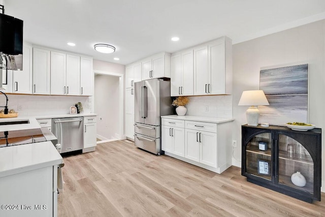 kitchen with backsplash, white cabinets, sink, light wood-type flooring, and stainless steel appliances