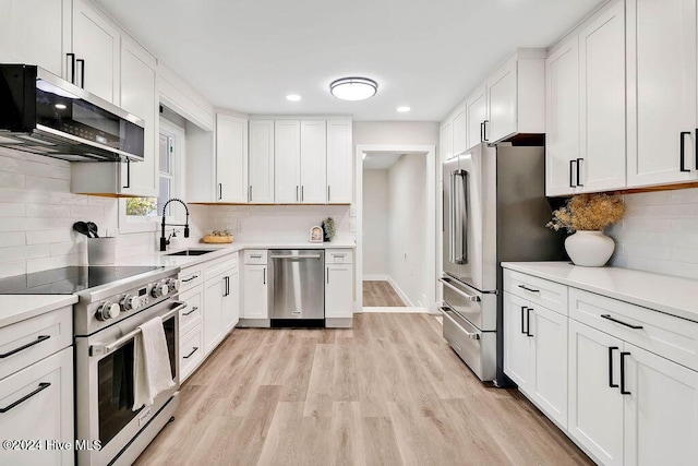 kitchen with white cabinets, light wood-type flooring, high quality appliances, and sink