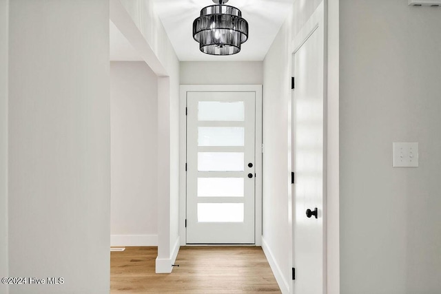 entryway with light hardwood / wood-style floors and an inviting chandelier