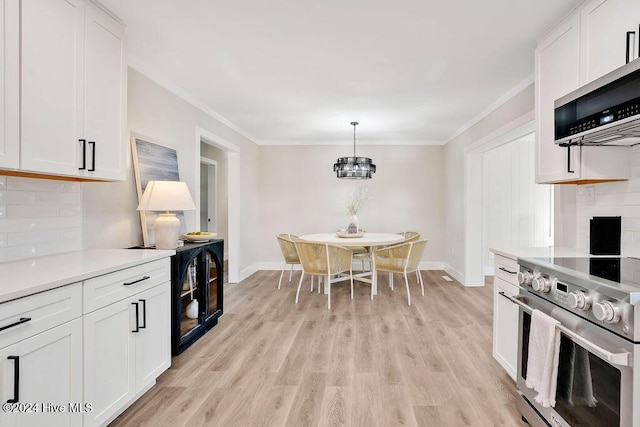 kitchen featuring white cabinets, decorative backsplash, appliances with stainless steel finishes, and light hardwood / wood-style flooring