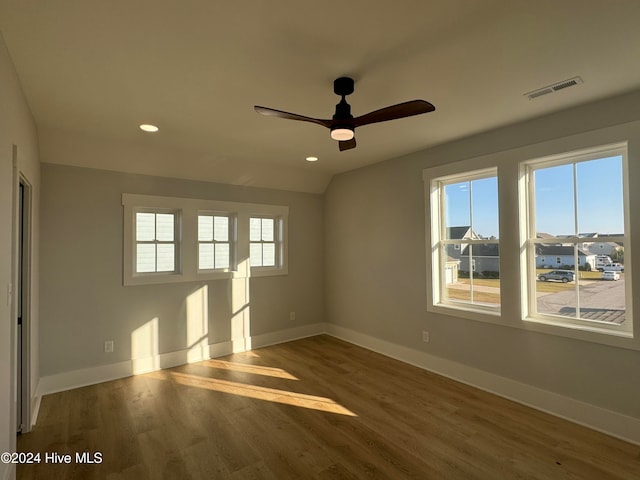 empty room with lofted ceiling, hardwood / wood-style flooring, and ceiling fan