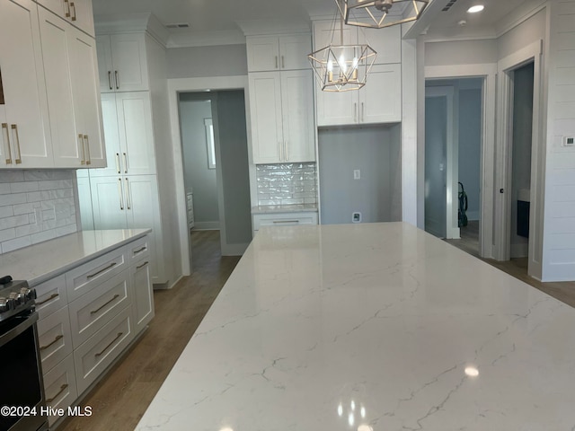 kitchen featuring white cabinets, light stone countertops, hanging light fixtures, and backsplash