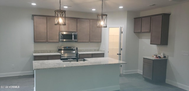 kitchen with a kitchen island with sink, sink, stainless steel appliances, and decorative light fixtures