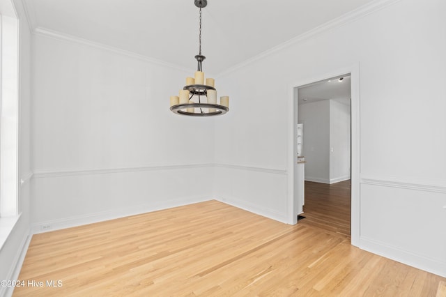 empty room with hardwood / wood-style flooring, ornamental molding, and a chandelier