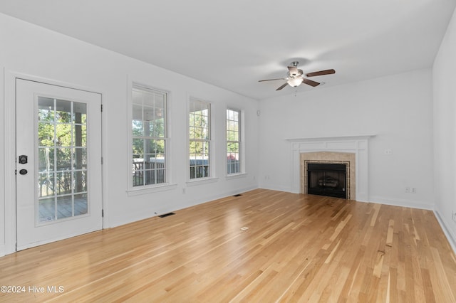 unfurnished living room featuring ceiling fan, a fireplace, and light hardwood / wood-style floors