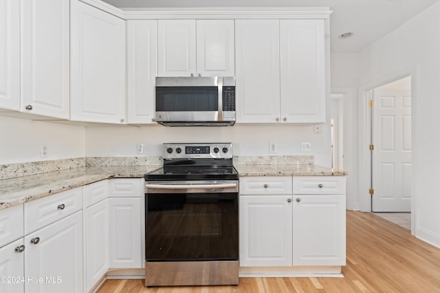 kitchen with white cabinetry, light wood-type flooring, light stone counters, and appliances with stainless steel finishes