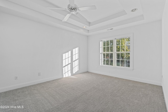 carpeted empty room with a raised ceiling and ceiling fan