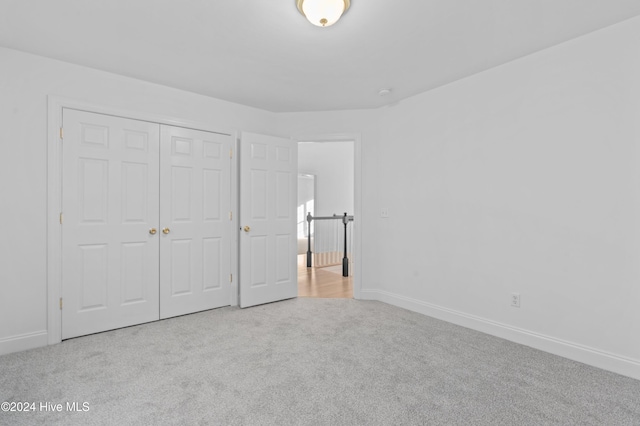 unfurnished bedroom featuring light carpet and a closet