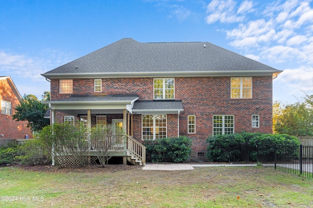 back of house featuring a deck and a lawn