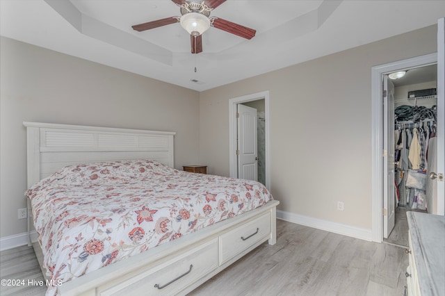 bedroom featuring a closet, ceiling fan, a spacious closet, and light hardwood / wood-style floors