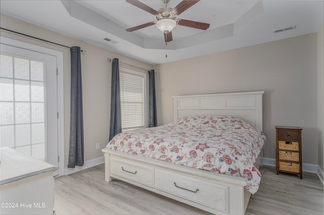 bedroom featuring light wood-type flooring, ceiling fan, and a raised ceiling