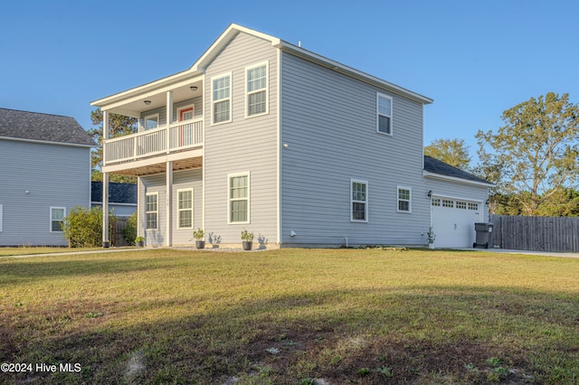 rear view of house with a balcony, a yard, and a garage