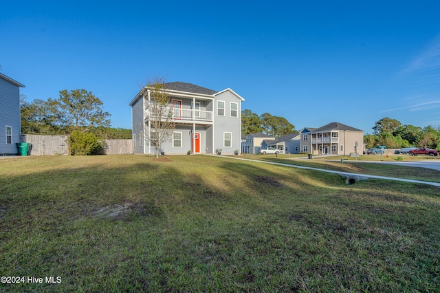 view of front of home with a balcony and a front yard