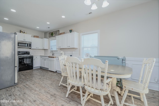 kitchen with stainless steel appliances, light hardwood / wood-style floors, sink, white cabinets, and decorative backsplash