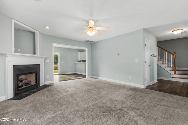 unfurnished living room with ceiling fan and dark colored carpet