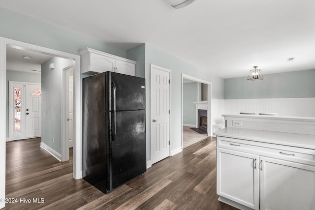 kitchen with a notable chandelier, dark hardwood / wood-style floors, white cabinets, and black fridge