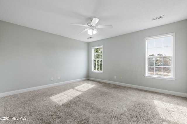 carpeted spare room featuring ceiling fan and a textured ceiling