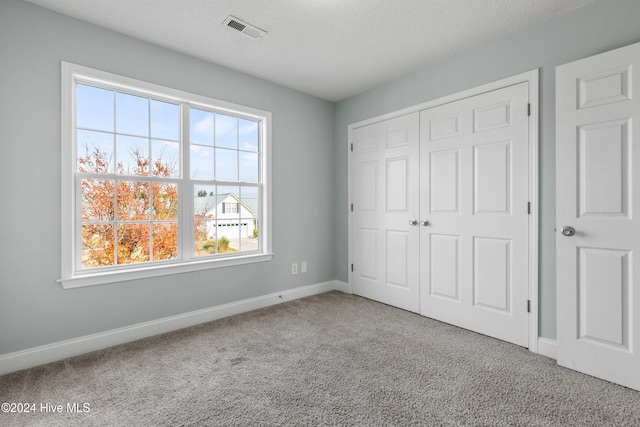 unfurnished bedroom with a closet, a textured ceiling, and carpet