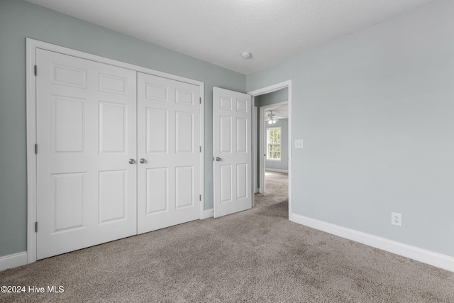 unfurnished bedroom featuring carpet floors, a textured ceiling, and a closet