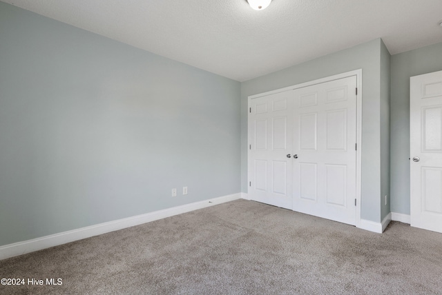 unfurnished bedroom with carpet flooring, a textured ceiling, and a closet