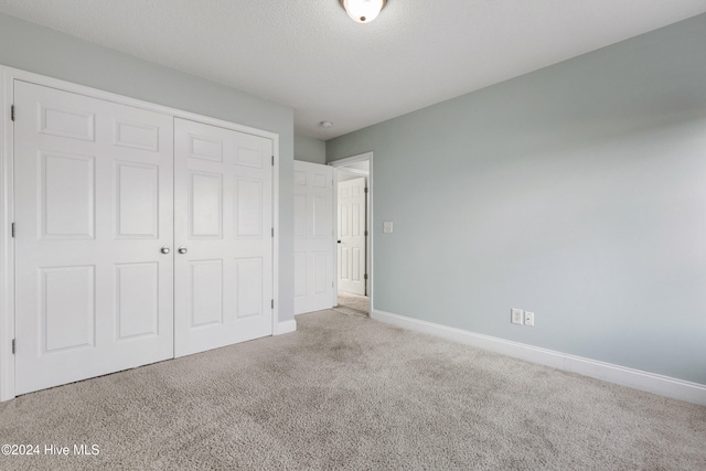 unfurnished bedroom with carpet floors, a closet, and a textured ceiling