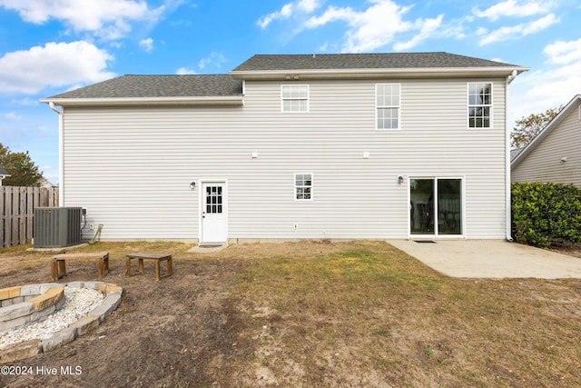 rear view of property featuring cooling unit, a yard, a fire pit, and a patio area