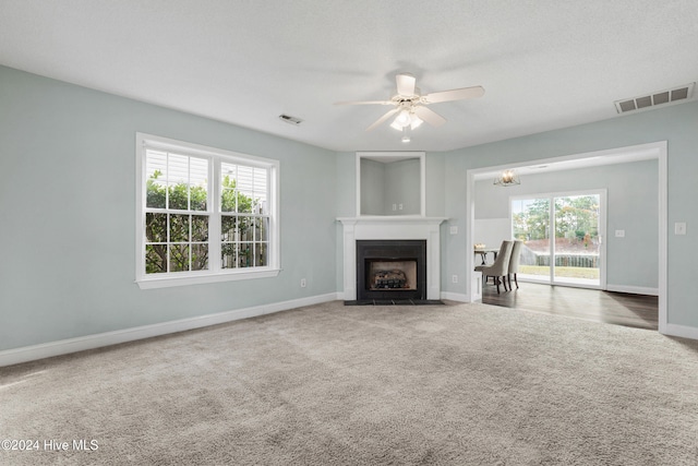 unfurnished living room featuring ceiling fan and carpet flooring