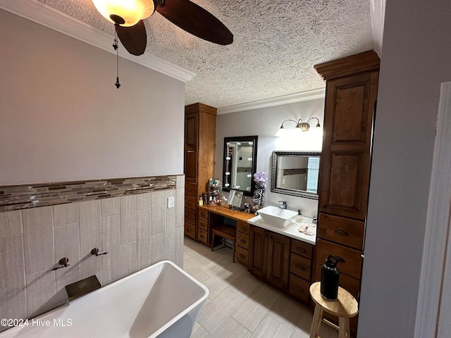 bathroom featuring ornamental molding, vanity, a textured ceiling, a bathing tub, and ceiling fan