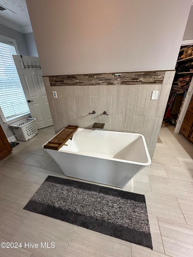 bathroom featuring a bath, tile patterned flooring, tile walls, and crown molding