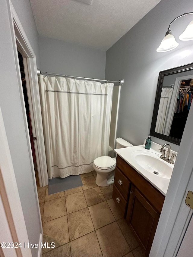 full bathroom featuring tile patterned flooring, a textured ceiling, shower / bath combo with shower curtain, vanity, and toilet