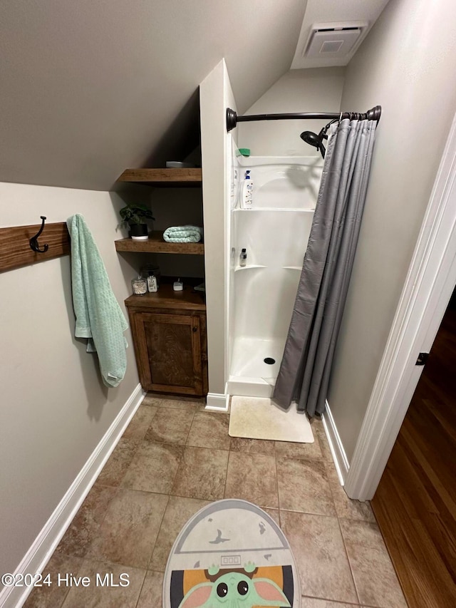 bathroom featuring a shower with curtain, tile patterned flooring, and lofted ceiling