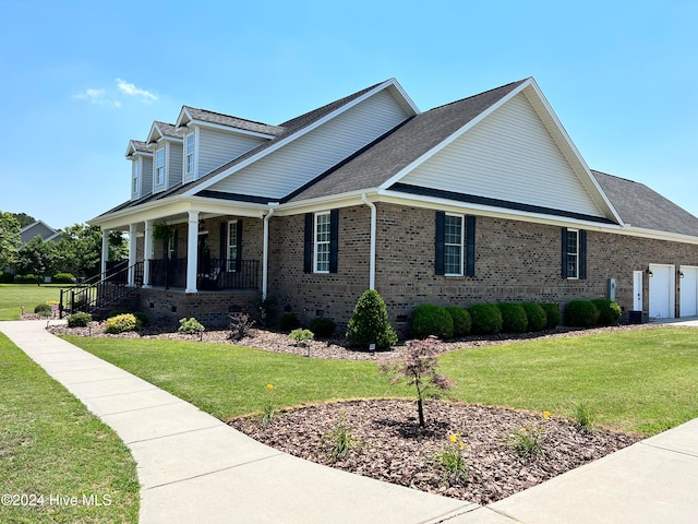 view of side of home featuring a garage, a lawn, and covered porch