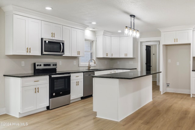 kitchen featuring stainless steel appliances, a kitchen island, hanging light fixtures, and white cabinetry