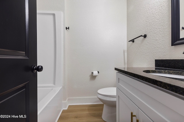 bathroom featuring hardwood / wood-style flooring, vanity, toilet, and a tub