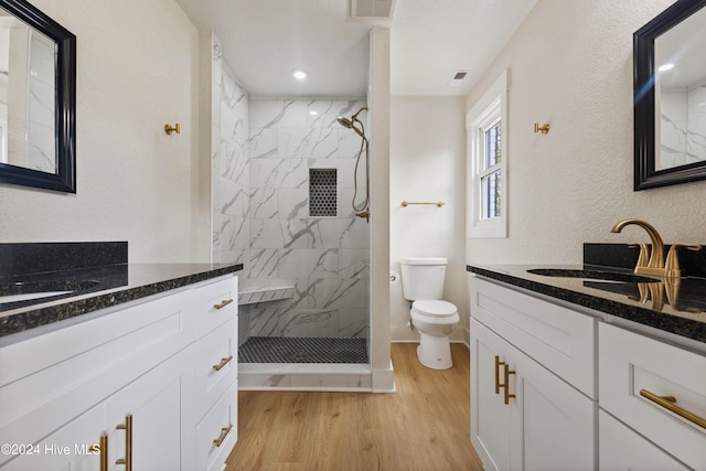 bathroom with toilet, hardwood / wood-style floors, vanity, and tiled shower