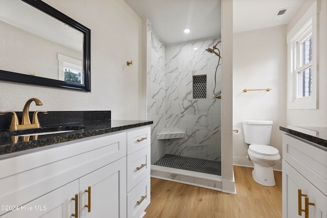 bathroom featuring hardwood / wood-style floors, vanity, toilet, and tiled shower