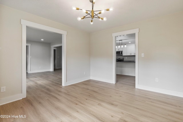 spare room with a chandelier and light hardwood / wood-style flooring