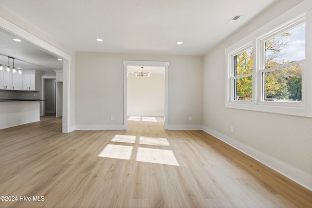 unfurnished living room with a chandelier and light hardwood / wood-style flooring