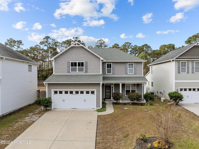 view of property featuring a garage, a front yard, and a porch