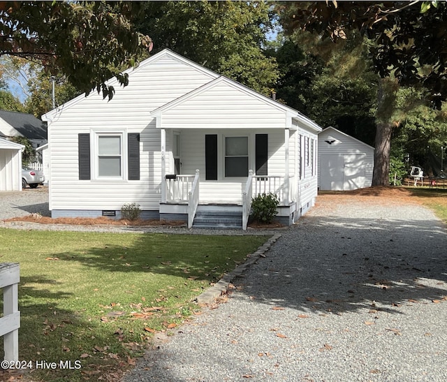 bungalow with a front yard, covered porch, a garage, and an outdoor structure