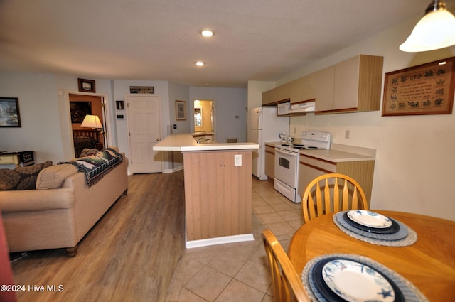 kitchen with hanging light fixtures, ventilation hood, white appliances, a center island, and light wood-type flooring